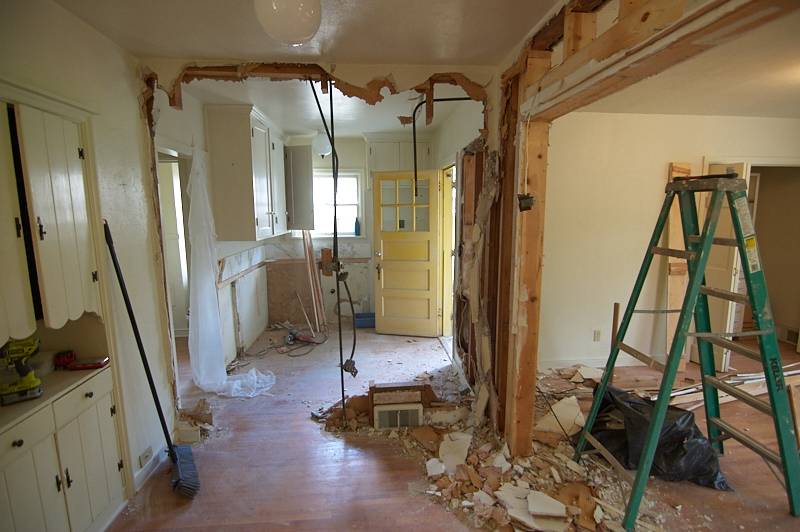 A room under construction with a green ladder and a push broom.