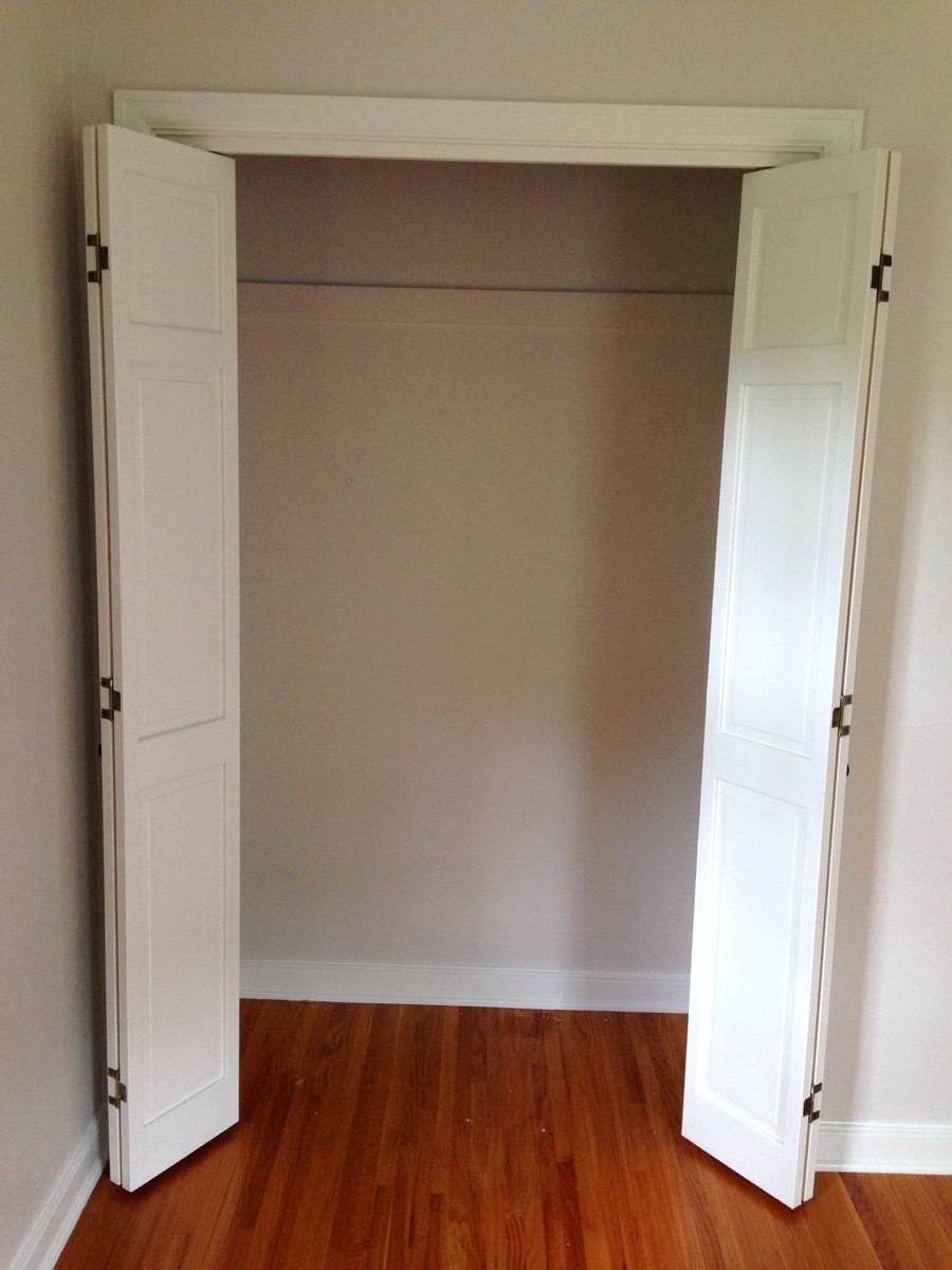 White doors open to empty closet in a room with warm-colored wooden floor.