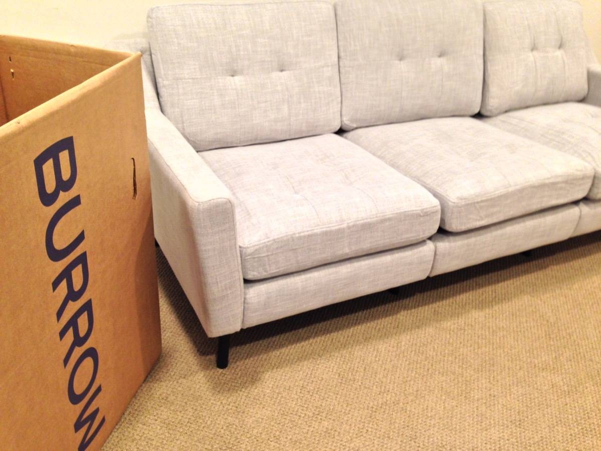 A box reading burrow sits next to a white modern couch