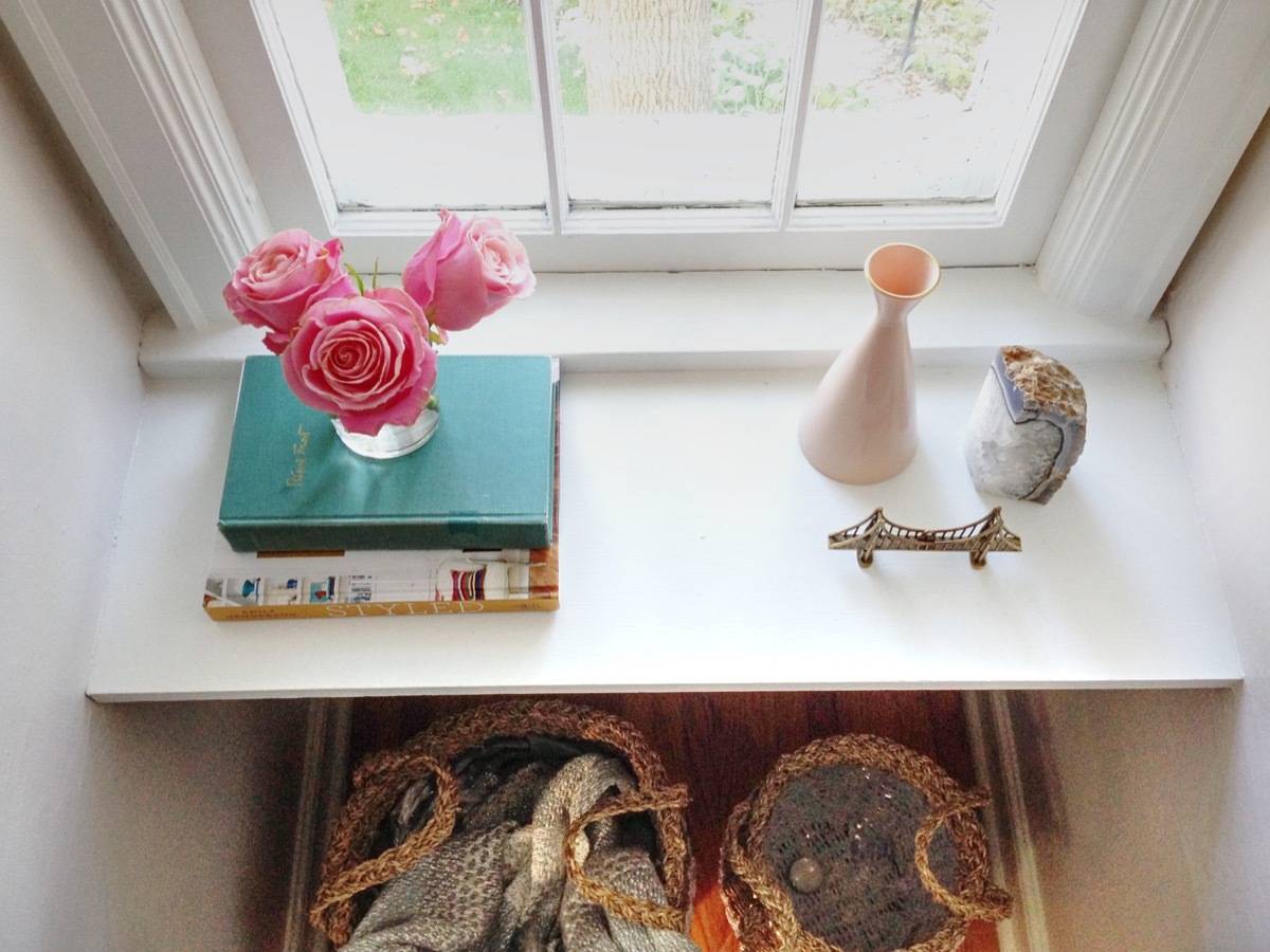 A desk has books, roses and other decorative items on it.