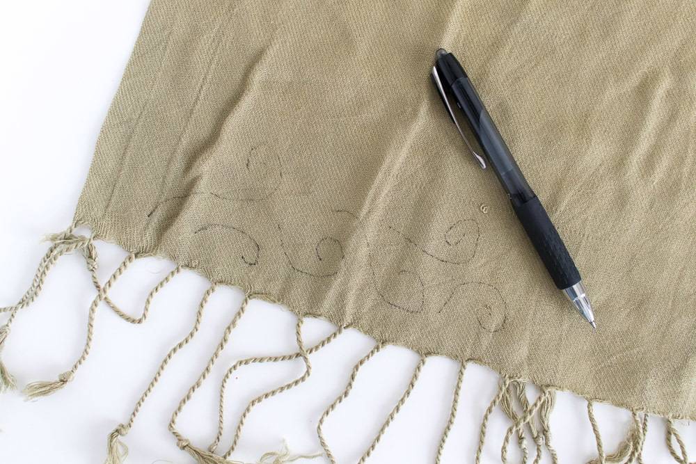A black pen resting on a brown fabric with marks on it.