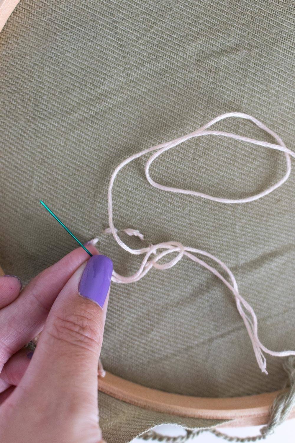 A person with purple fingernails is working with string.