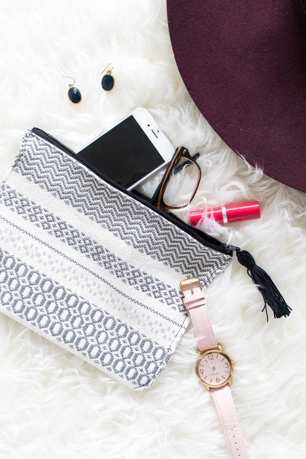 a clutch back in grey and white with a watch and iphone
