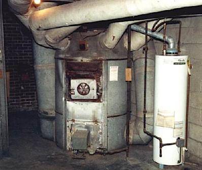 A dark room shows a large metal water heater.