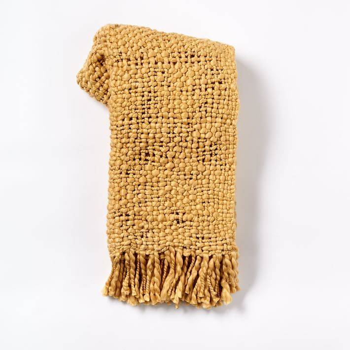 A folded yellow scarf on a white surface.