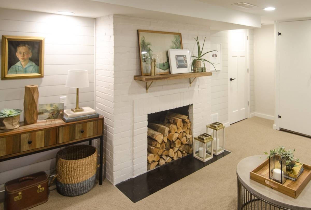 Decorations and logs in a fireplace in a white room.