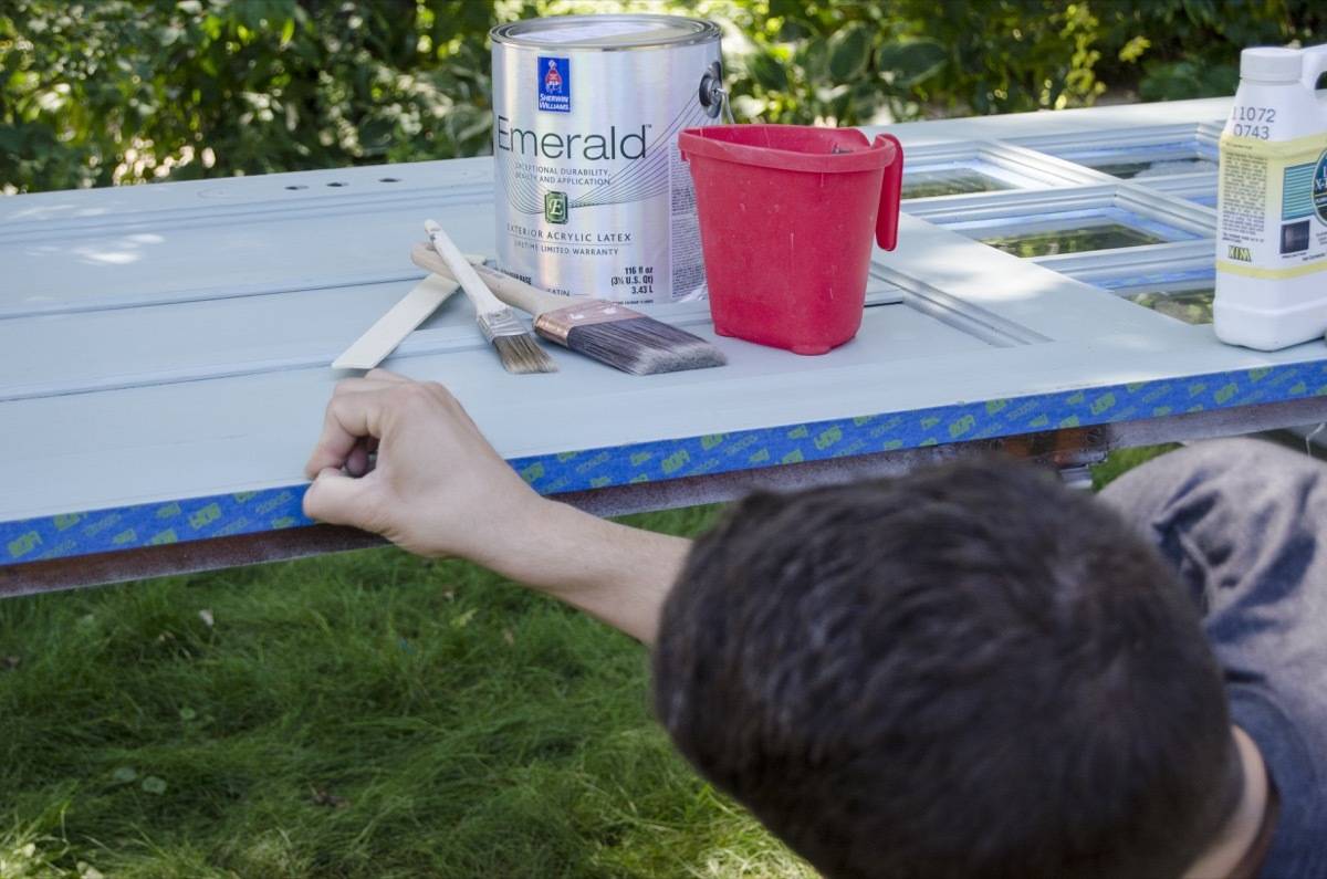 A person is doing some work on a blue table outside.