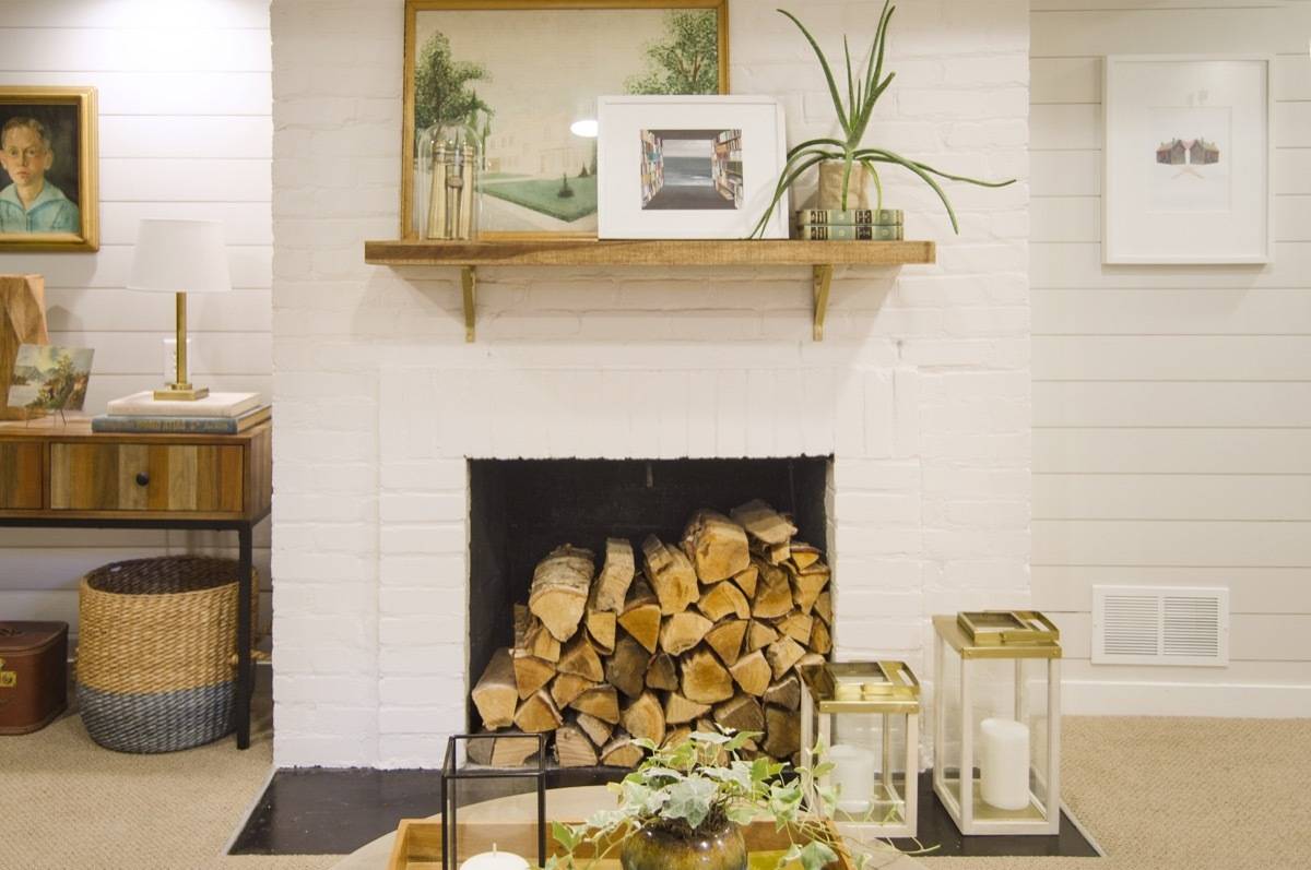 White brick fireplace that holds chopped firewood.