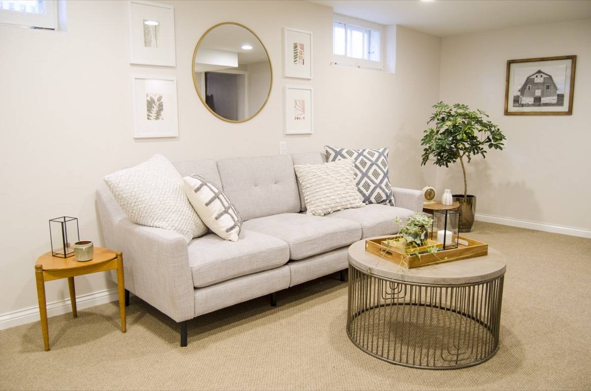A living room with an off white couch, a couple of accent pillows, a side table next to it and a round coffee table in front of the couch.