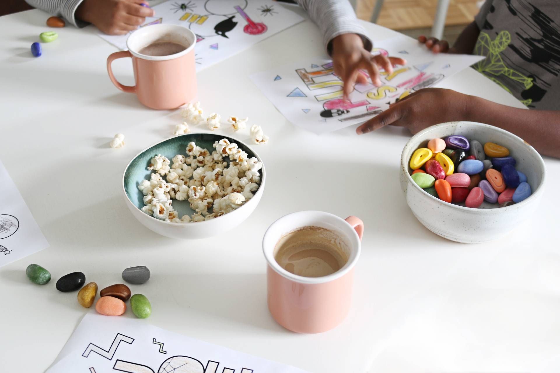 Peoplecare next to a bowl of popcorn, candy and hot cocoa mugs are on a table.