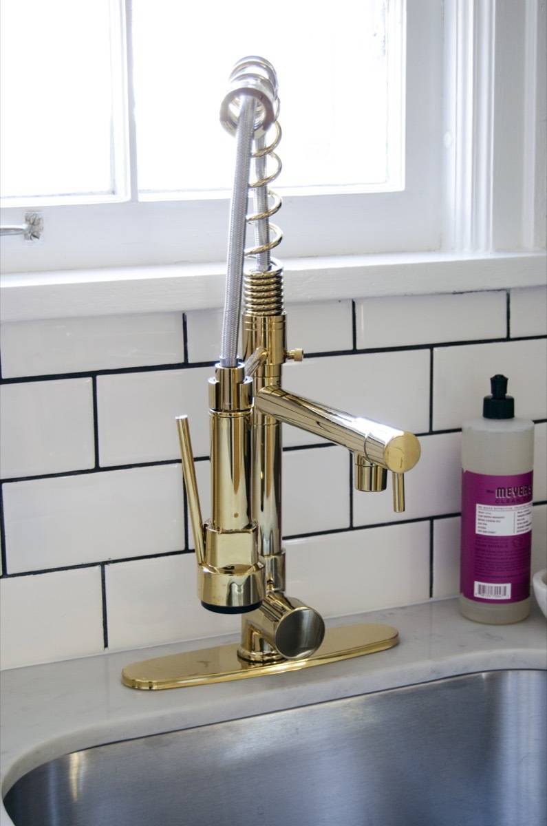 Gold kitchen faucet detail with stainless steel sink