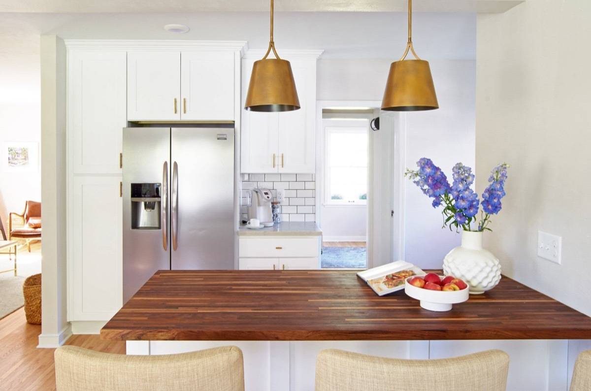 Curbly House kitchen, over butcher block island, white cabinets with gold hardware