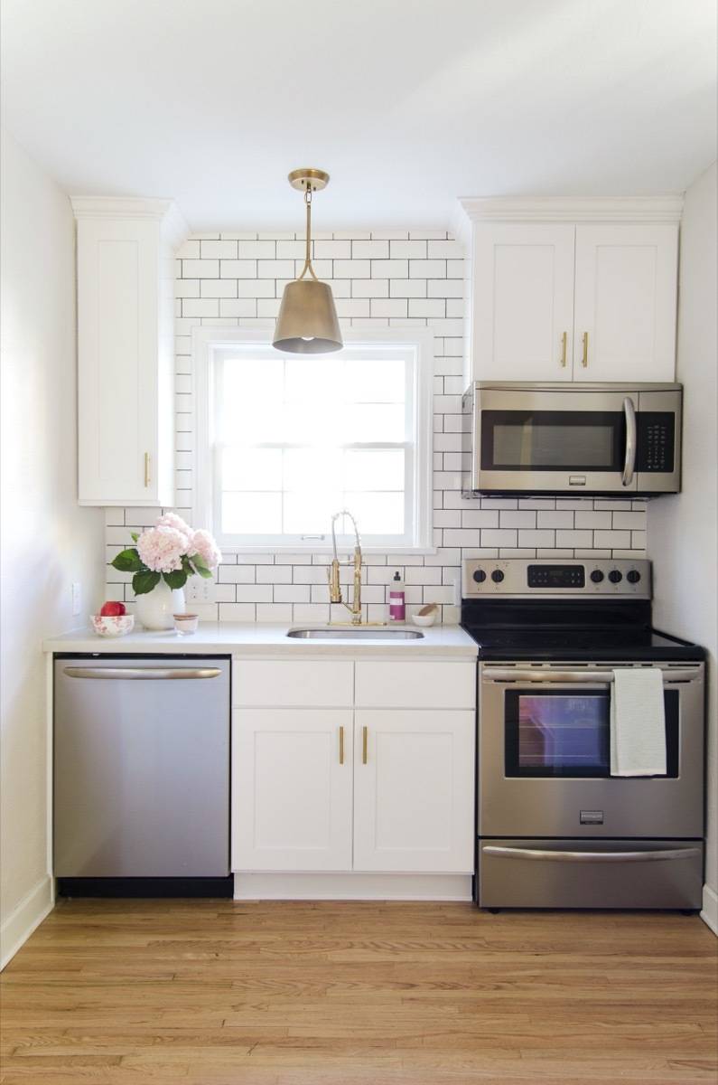 Kitchen, after - stainless steel appliances, gold accents, subway tile with black grout