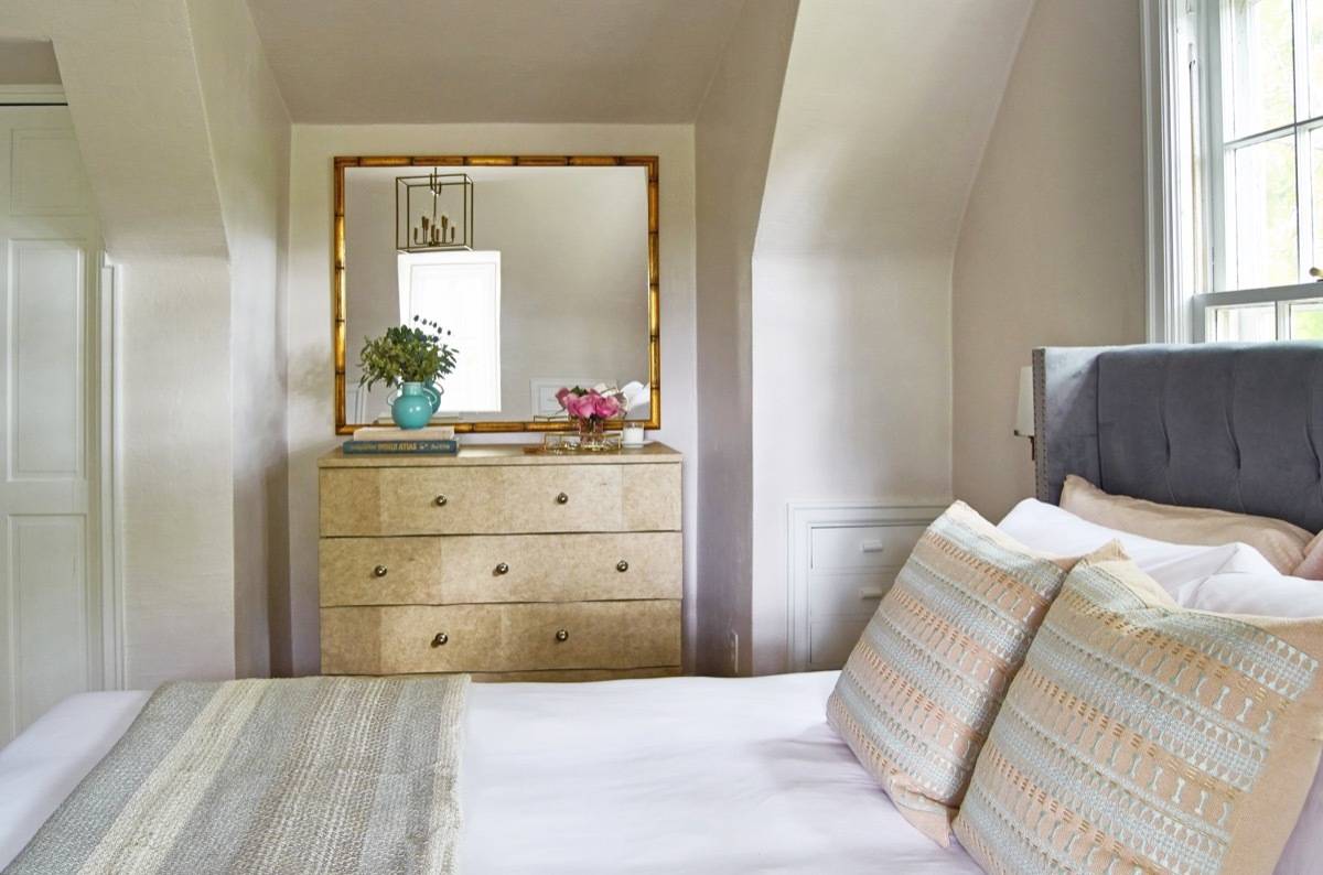 Huge gold trim mirror above bedroom dresser, marble front drawers