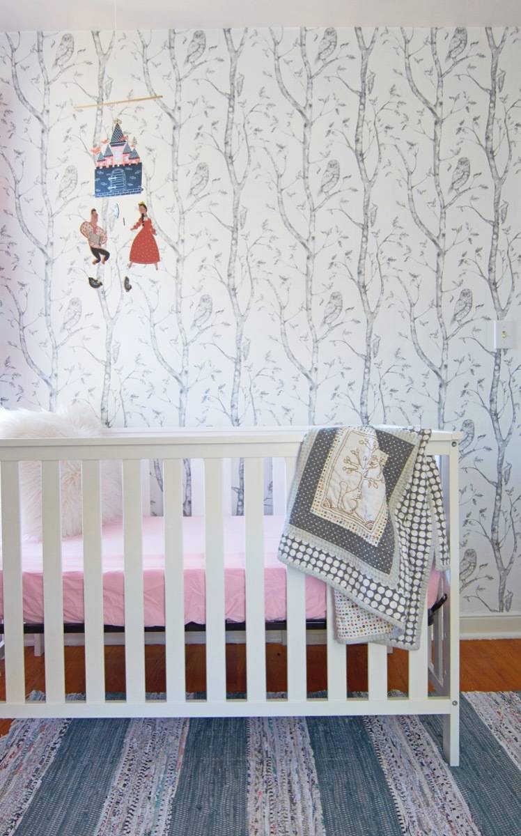 Crib with mobile and tree wallpaper