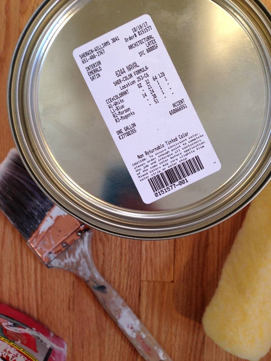 A price tag sticker is attached to the top on a paint can next to a brush.