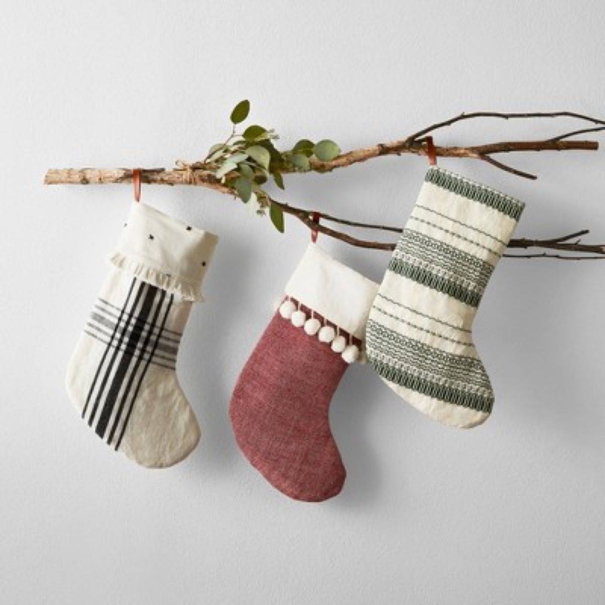 Three stockings hang from a small twig.