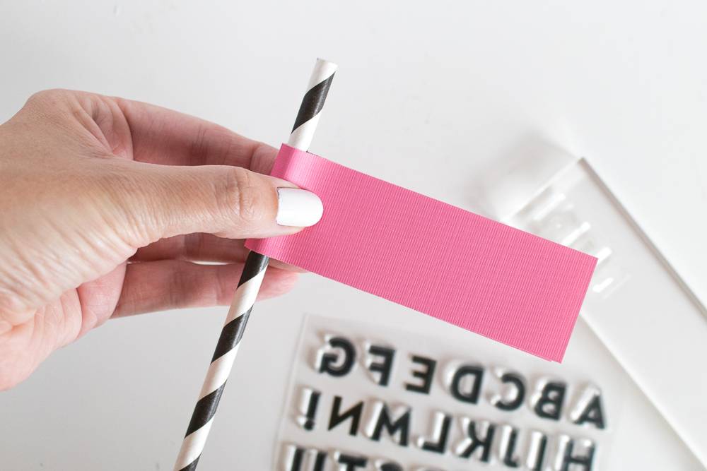 A black and white swirled straw with a piece of pink fabric wrapped around it.