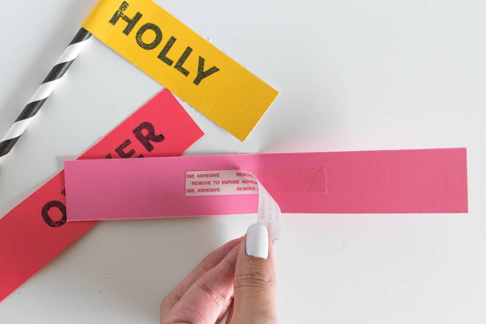 A person pulling a sticker off of a pink strip of paper.