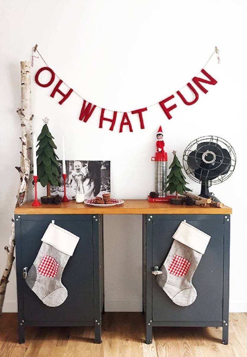 "Oh what fun" banner hangs above a table with Christmas decor including stockings on the front.