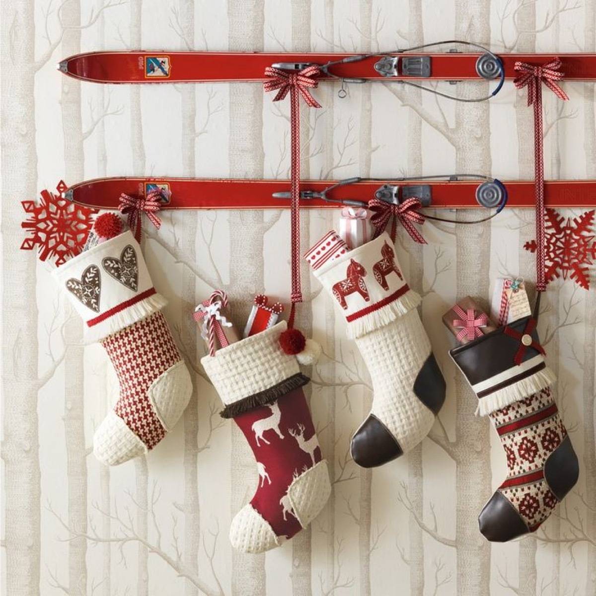 Four Christmas stockings are stuffed and hanging from a red bar on the wall.