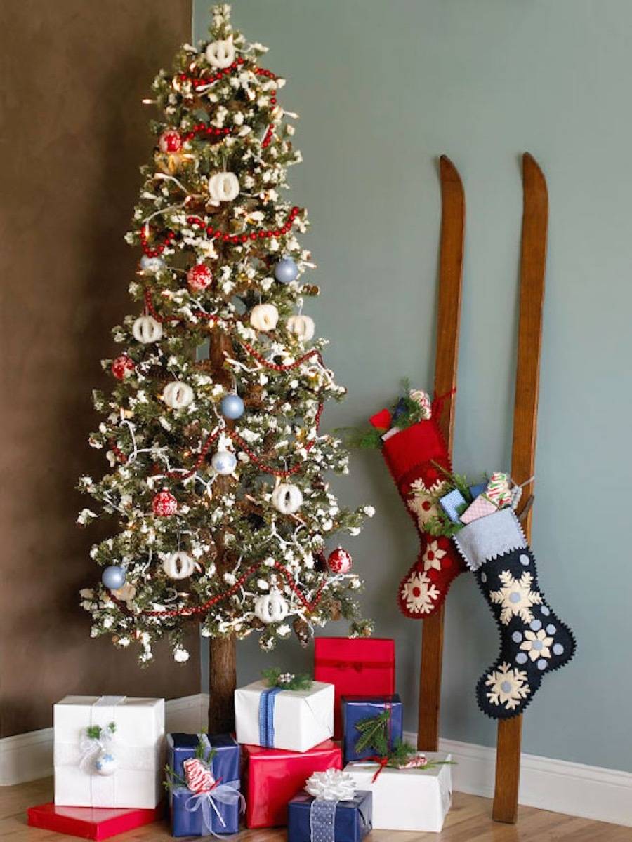 A decorated Christmas tree in a corner next to a pair of wooden skis with stocking hanging form them and presents under the tree.