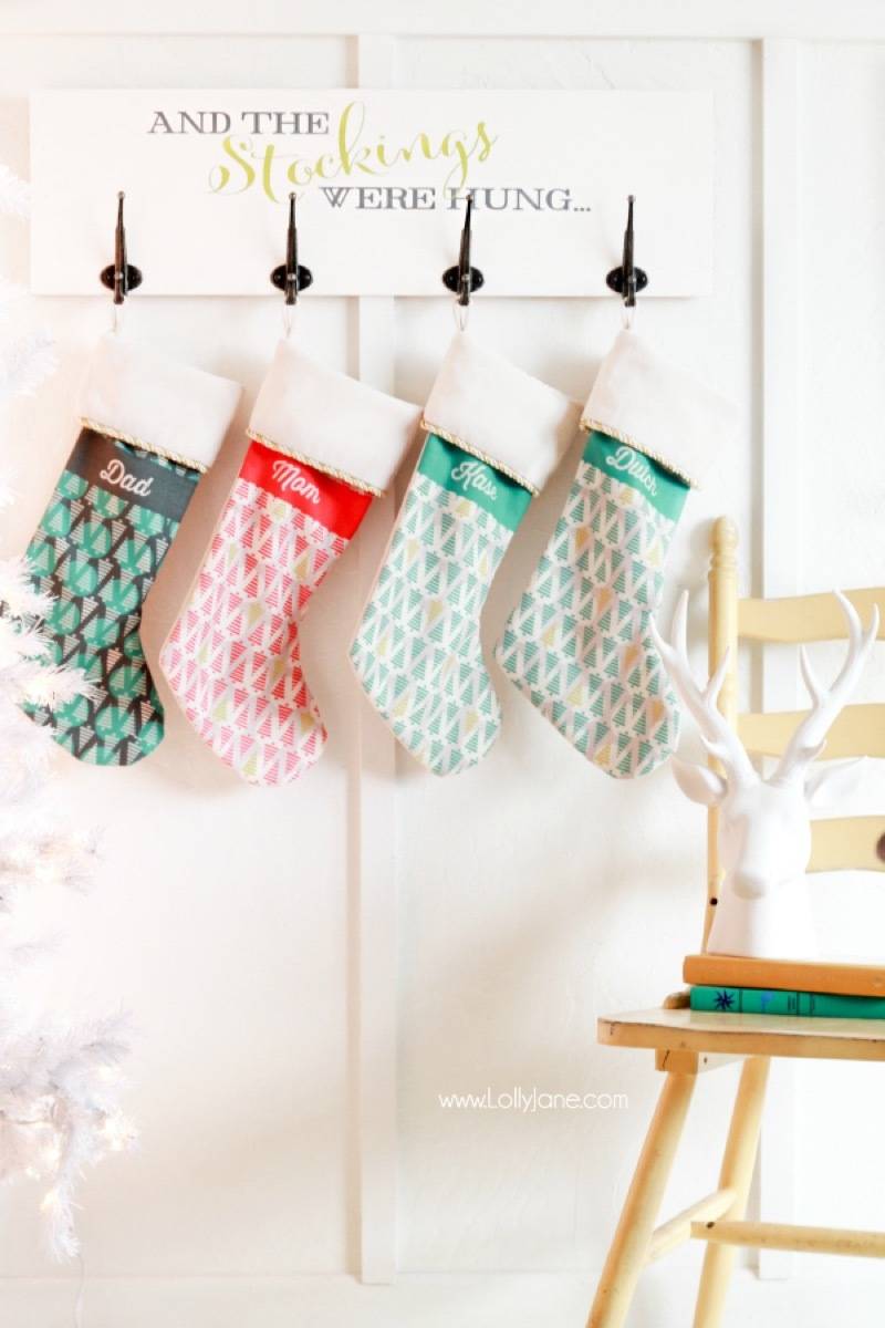 Four Christmas stockings are hanging from a white wall.