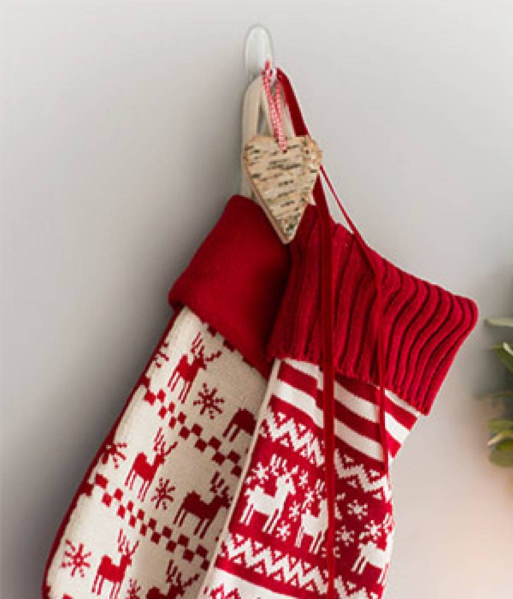 Two red and white mittens are hanging from a wall.