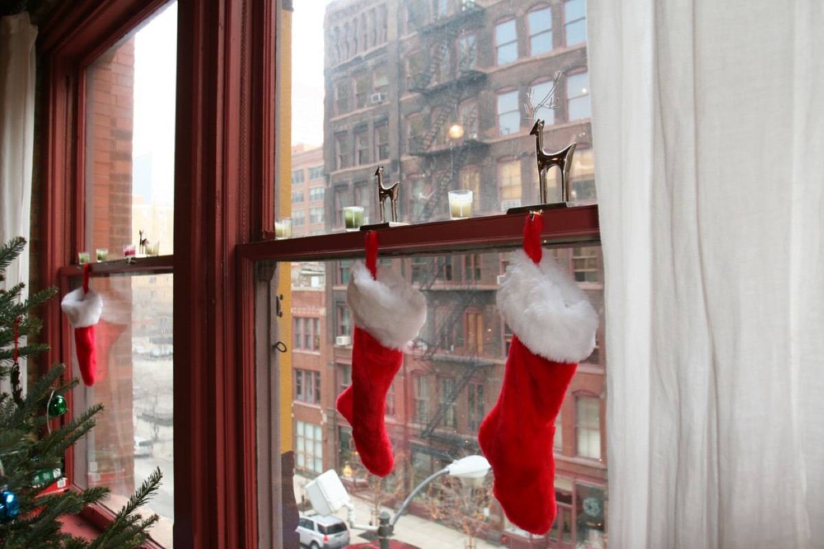 Three Christmas stockings hand in windows of an apartment high above the street.
