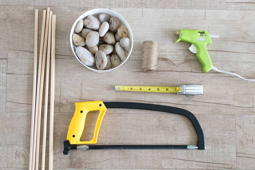 A glue gun and other tools near a cup full of rocks.