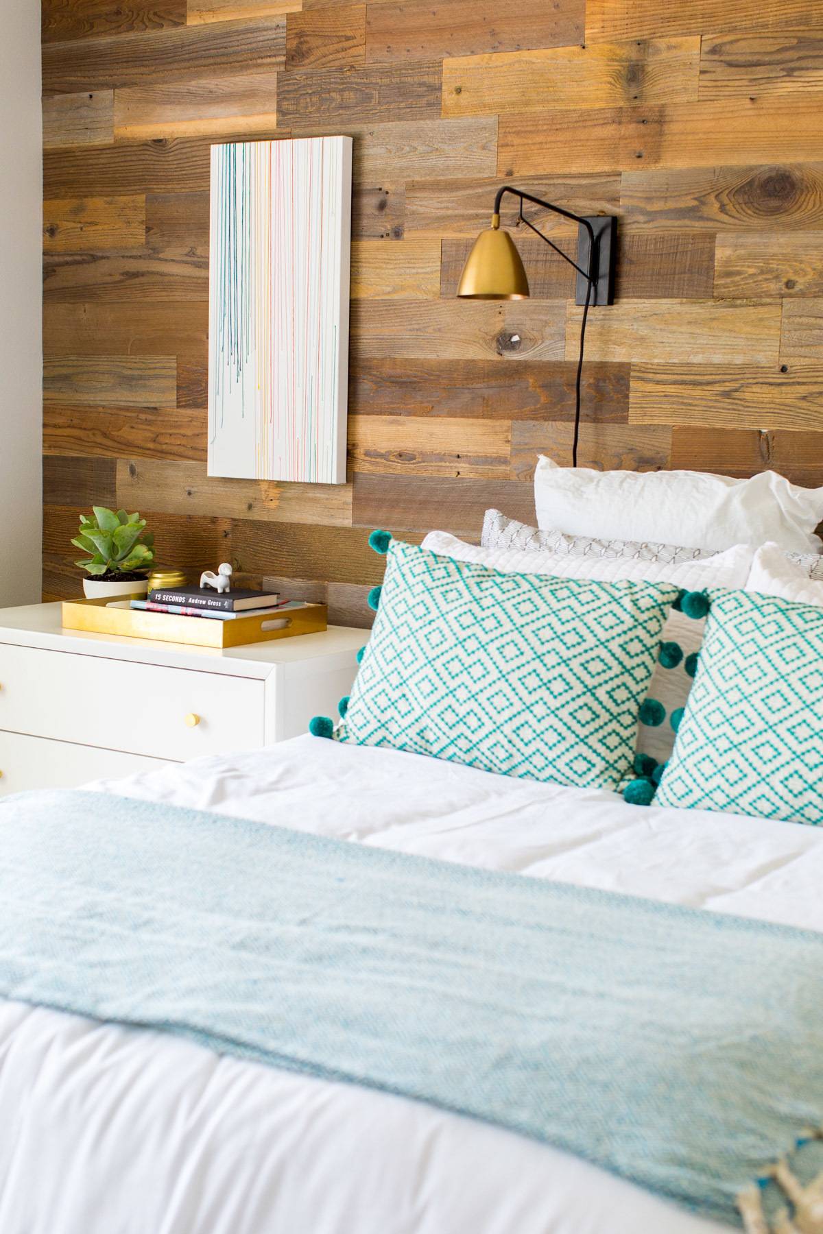 A cozy looking bedroom with a wood accent wall.