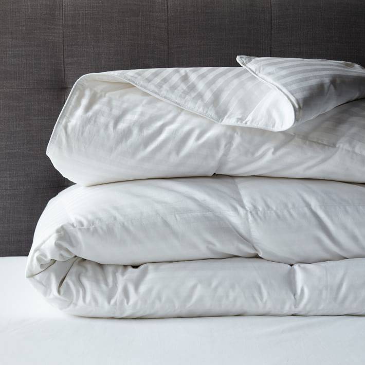 Fluffy white comforter folded on top of white sheets.