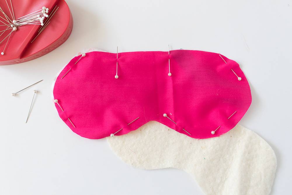 Straight pins hold pink cloth in the shape of an eye mask together.