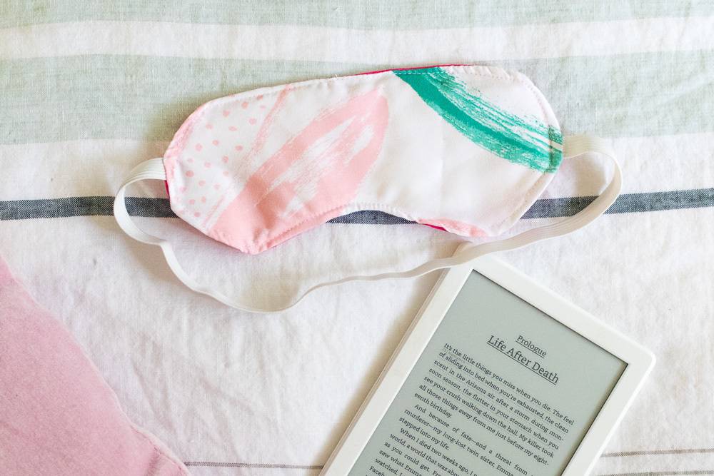 A sleep mask near an ereader.