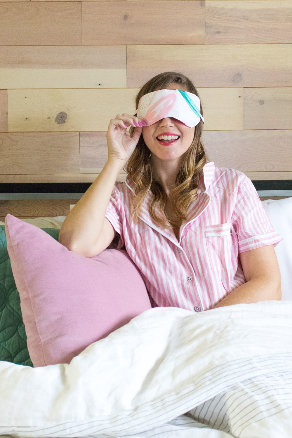 Woman sitting in bed with an eye mask on.