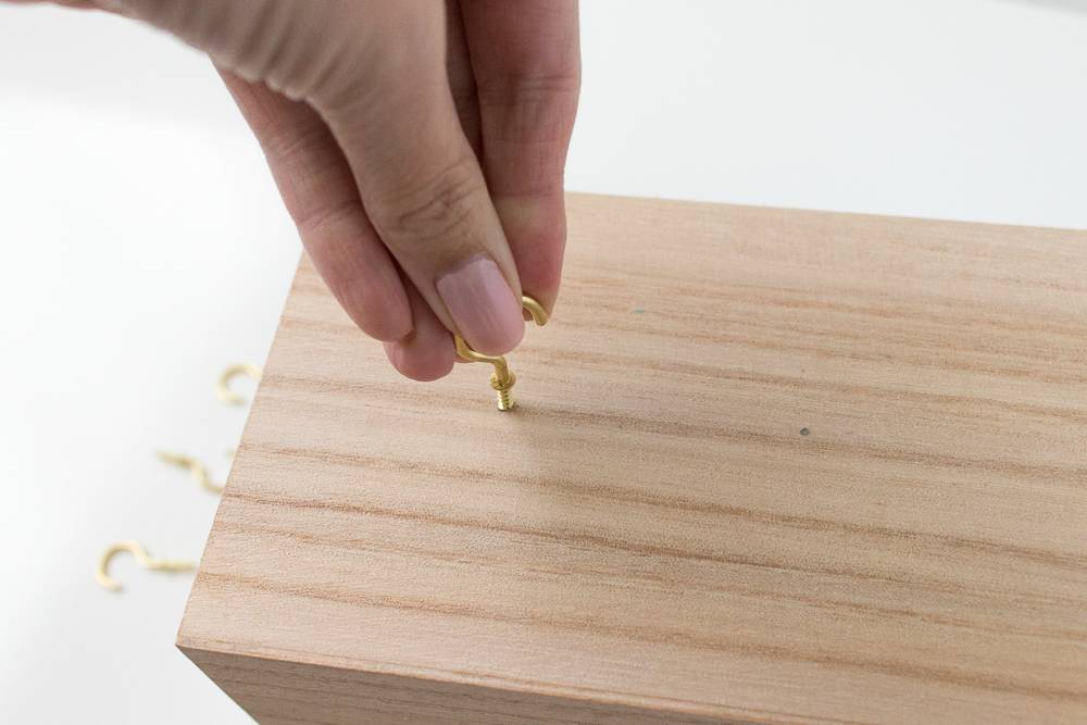 A person putting a screw on a piece of wood.