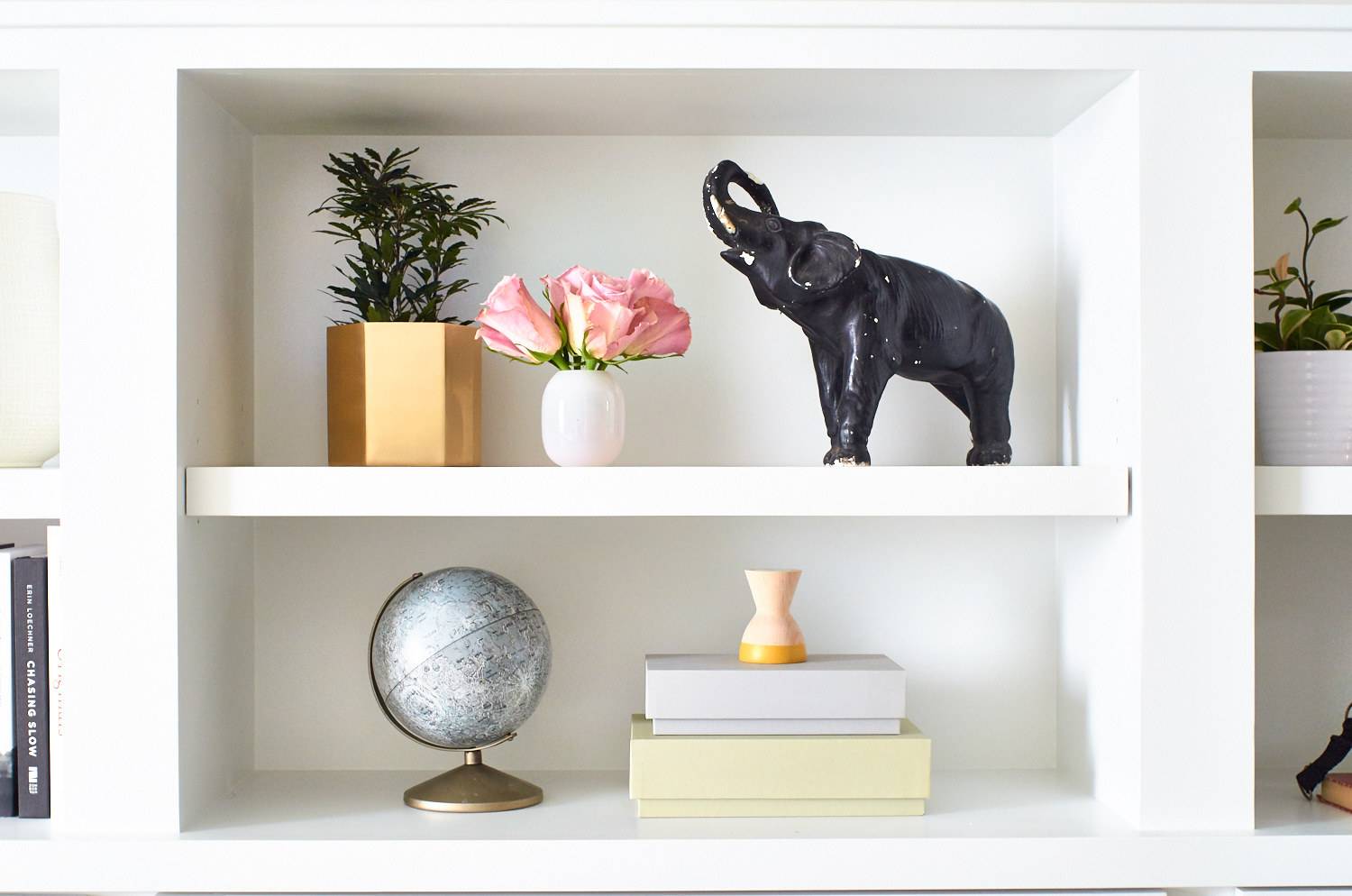 white wall shelf with a globe and elephant sculpture