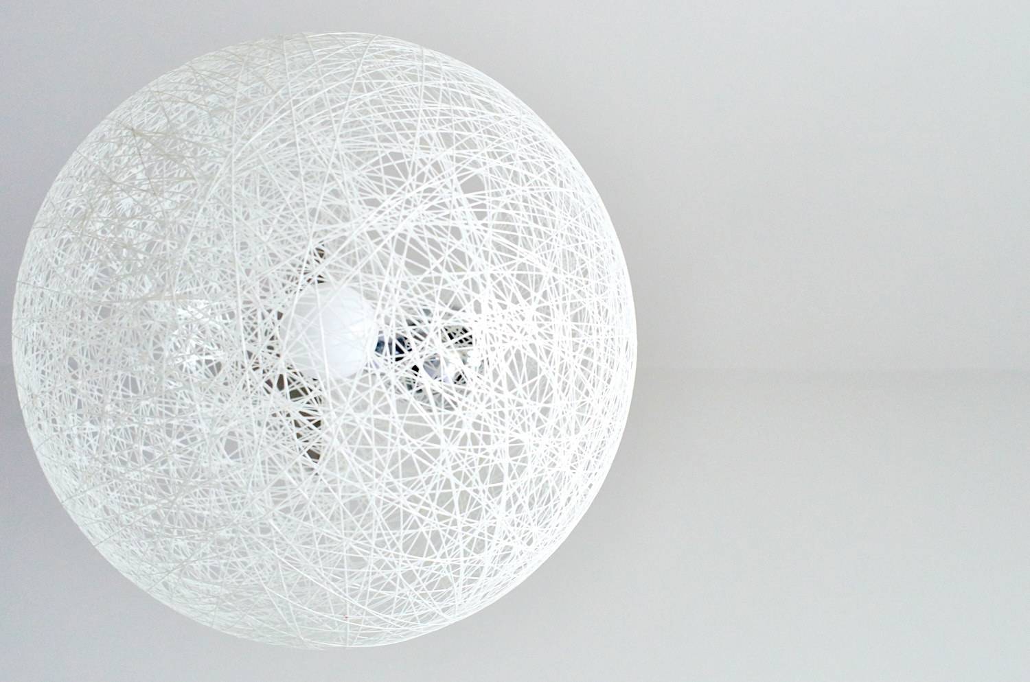 Modern light fixture designed as a sphere formed of white strands.