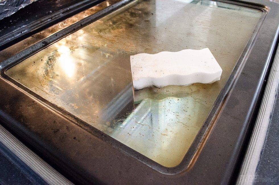 A white sponge is sitting on an open oven door.