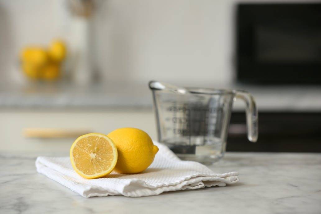 A lemon sliced in half is sitting on a napkin near a glass measuring cup.