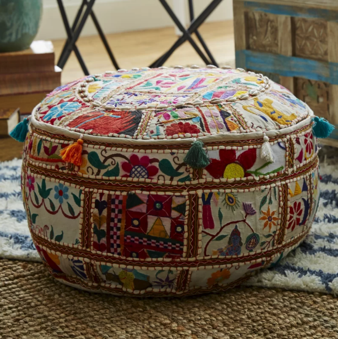 A colorful ottoman is sitting on the floor.