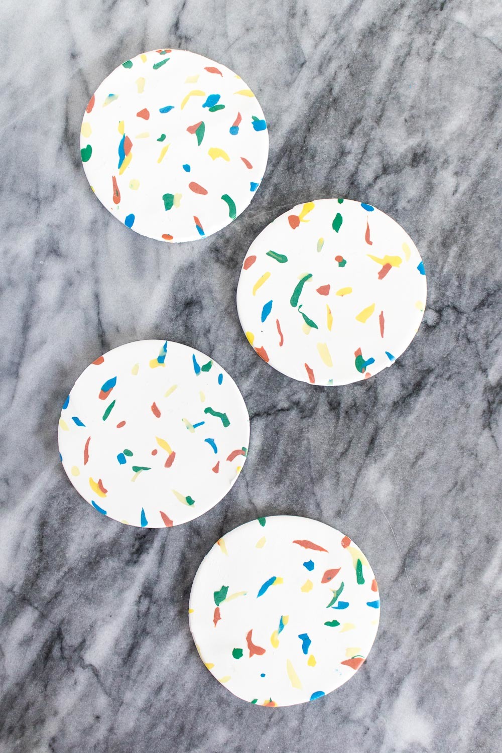 Four white cookies have sprinkles on them.