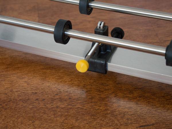 Black clamp with yellow knob on a metal bar.