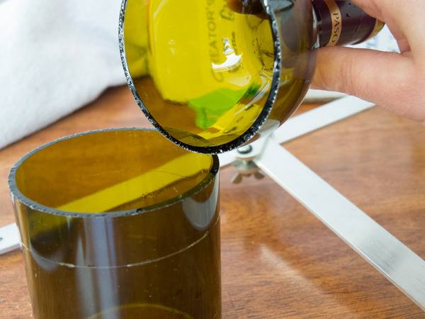 A person lifting the top off of a bottle with a yellow hue.