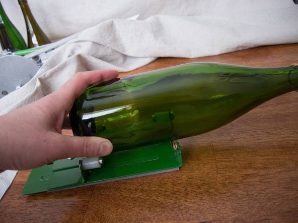 A person cutting a green glass bottle.