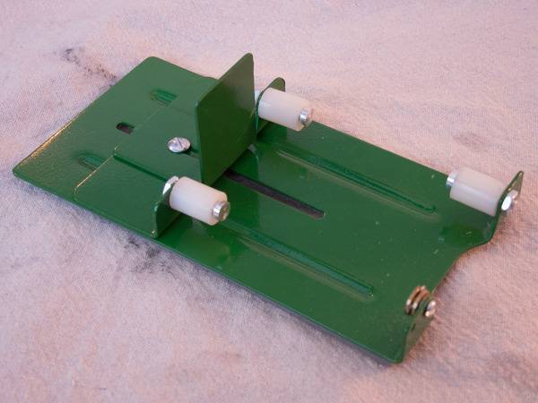 Green bottle cutter with white knobs laying on felt.