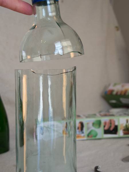 A broken glass bottle has the top held up.