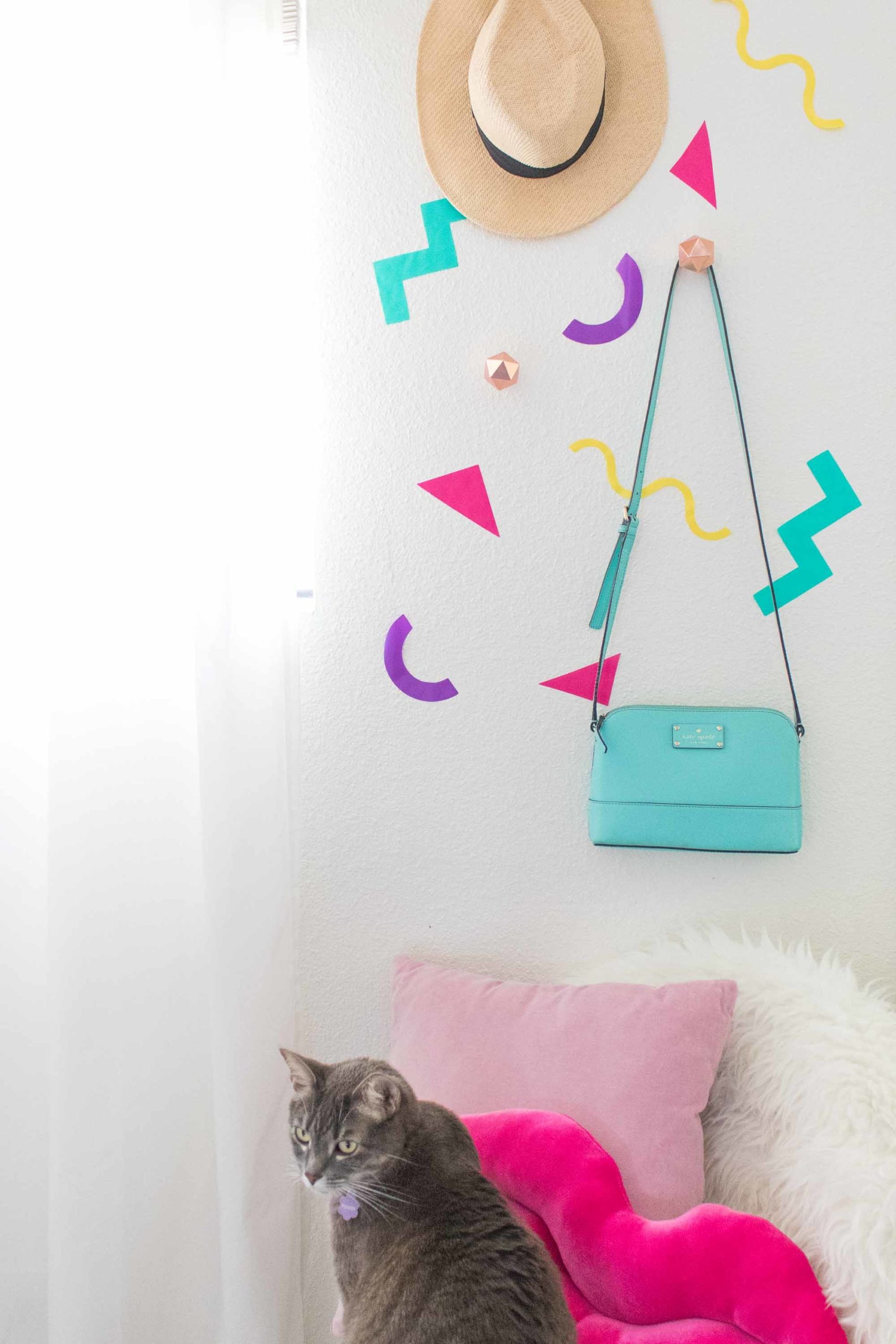 a cute cat on top of a white bed with cute decorating wall sticker and a hanging hat