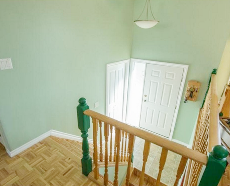 a stairwell with a brown banister and green walls