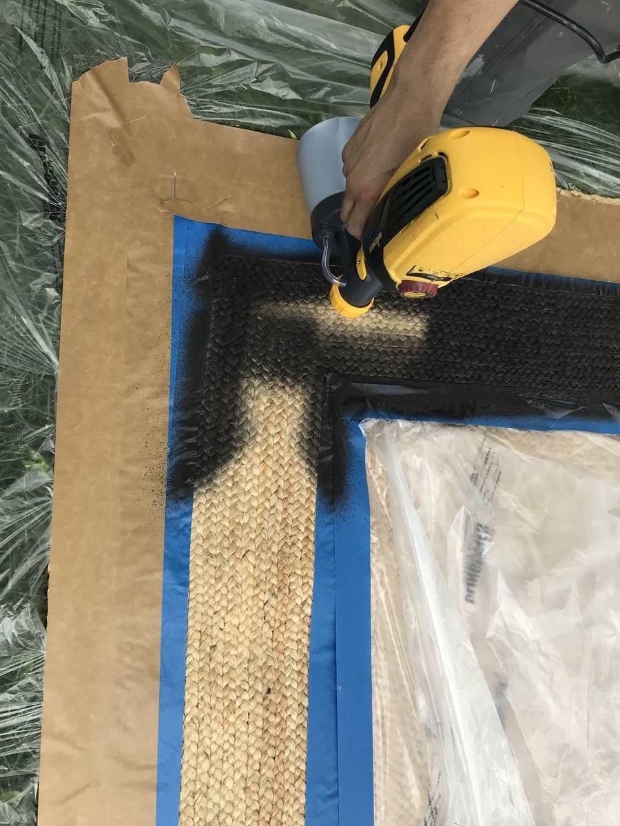 A person uses a paint brushing machine to put black paint on some wood.